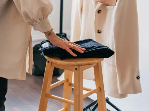 Person Folding Pants on a Stool - Putting Clothes Away by Merrill Oliver Douglas