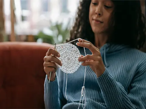 A Woman in Blue Knitted Sweater Holding a White Yarn - Holes by Julie Didcock-Williams