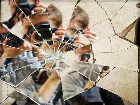 A photographer's reflection in a broken mirror